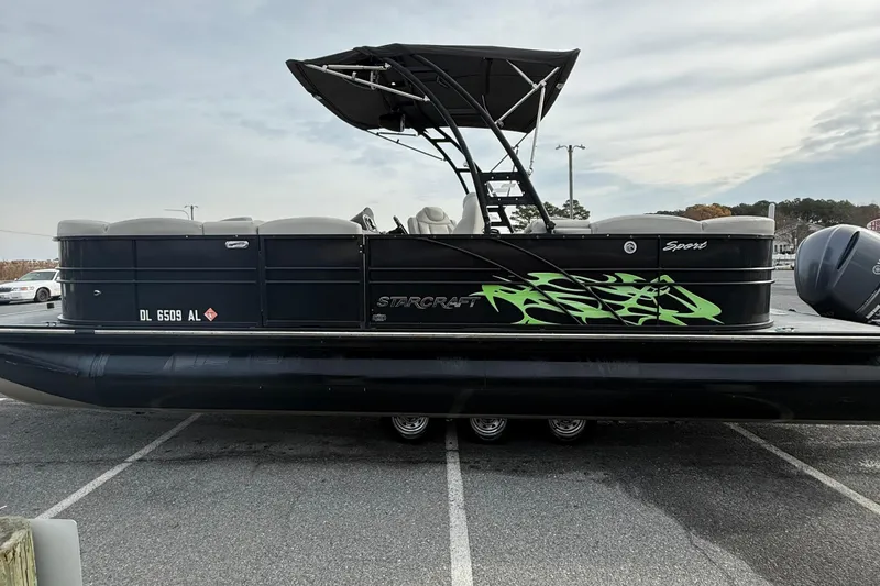 Slide: The Image of 2018 Starcraft SLS 5 pontoon boat with black exterior and green graphics. - 5