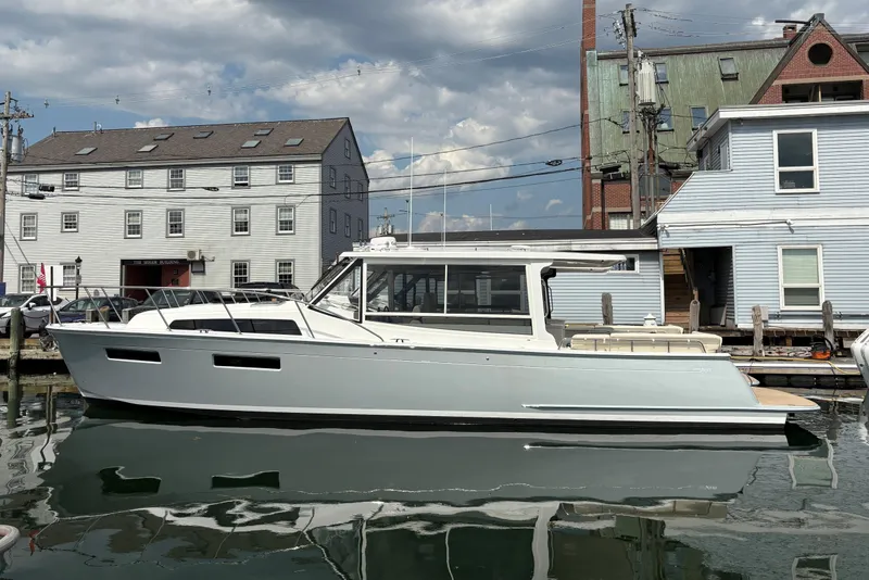 The Image of 2026 MJM 47 R yacht docked by historic buildings under a cloudy sky. - 1