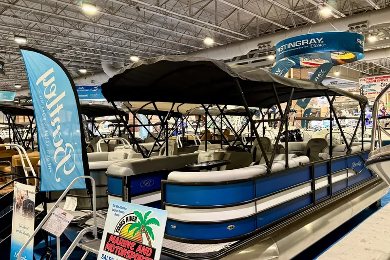 Slide: The Image of 2025 Bentley Pontoons Legacy 243 Navigator interior at a boat show, featuring modern seating and controls. - 3