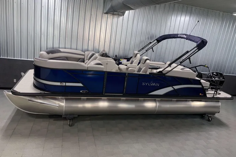 Slide: The Image of 2025 Sylvan L3 CLZ DH pontoon boat in a modern indoor showroom. - 0