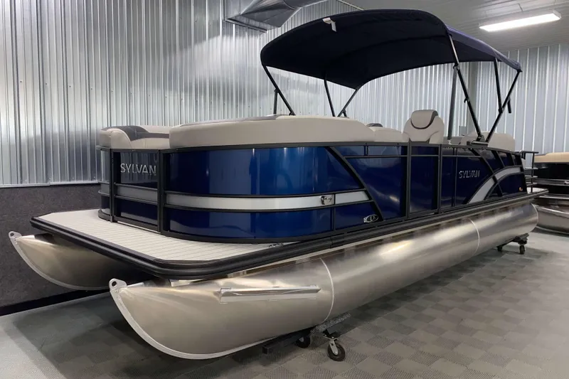Slide: The Image of 2025 Sylvan L3 CLZ DH pontoon boat in showroom, featuring sleek blue design and canopy. - 13