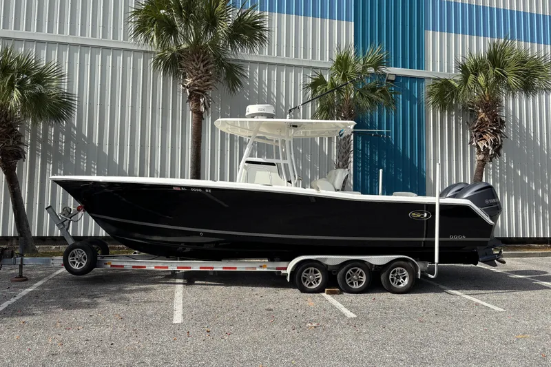 Slide: The Image of 2012 Sea Hunt Gamefish 29 boat on trailer, parked near palm trees. - 1