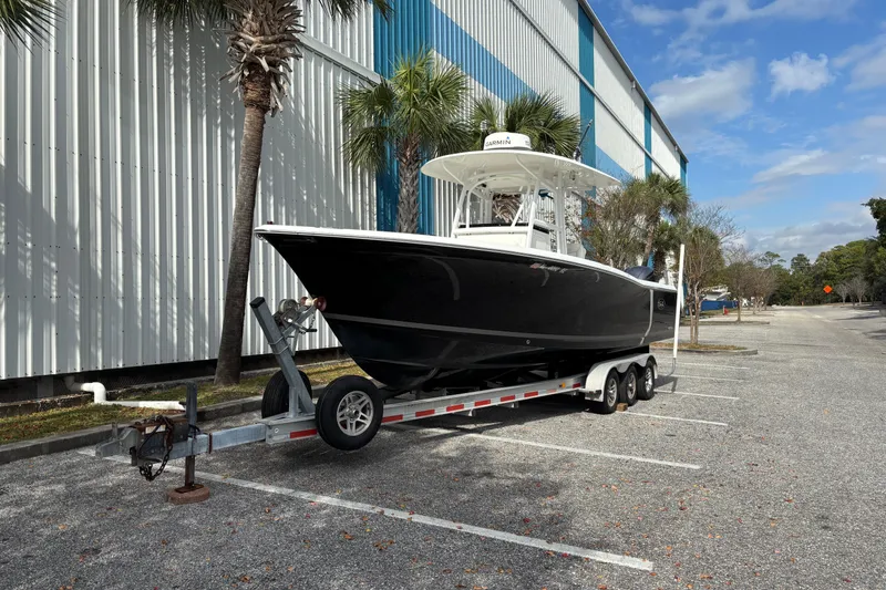 Slide: The Image of 2012 Sea Hunt Gamefish 29 boat on trailer, parked near a building with palm trees. - 4