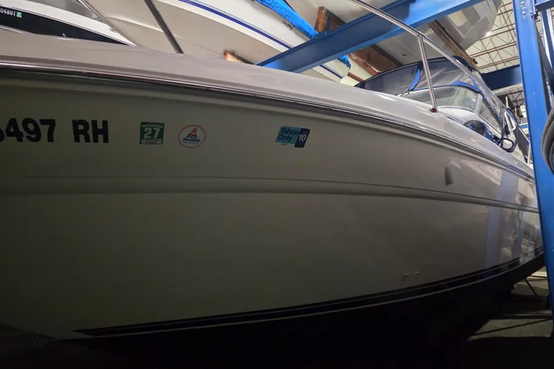 The Image of 1996 Sea Ray 290 Sundancer boat in storage, side view with visible decals. - 0