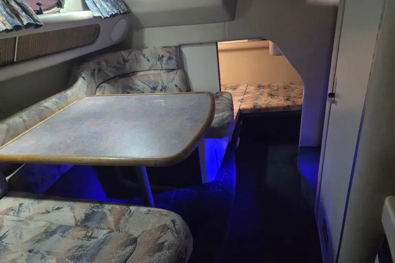 Slide: The Image of 1996 Sea Ray 290 Sundancer cabin interior with seating and table, blue ambient lighting. - 26
