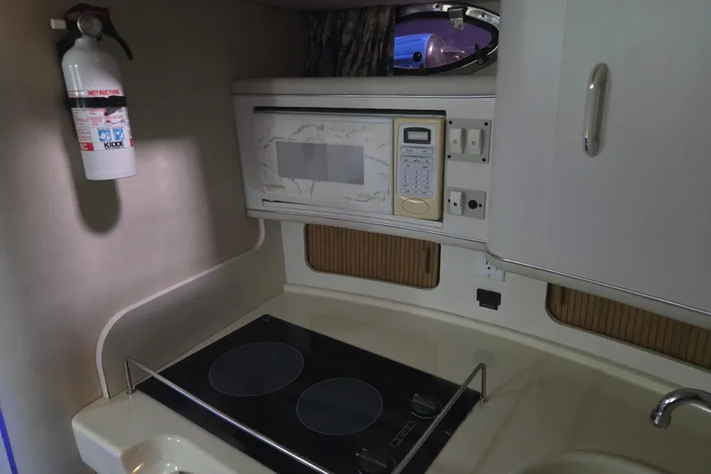 Slide: The Image of 1996 Sea Ray 290 Sundancer kitchen with stove, microwave, and fire extinguisher. - 29