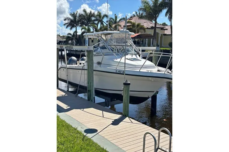 The Image of 2008 Century 2600 Walk-Around boat docked on a lift by a canal. - 0
