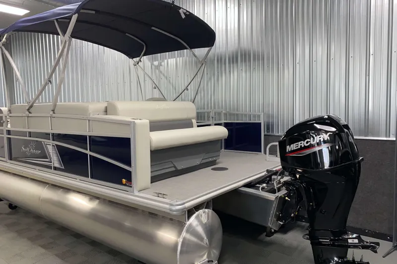 Slide: The Image of 2025 SunChaser Vista 20 CRB pontoon boat with Mercury outboard motor in a metal-walled showroom. - 18