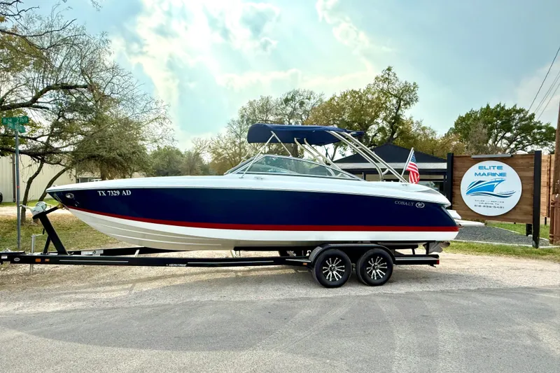Slide: The Image of 2006 Cobalt 272 boat on trailer, parked near Elite Marine sign, with American flag. - 10