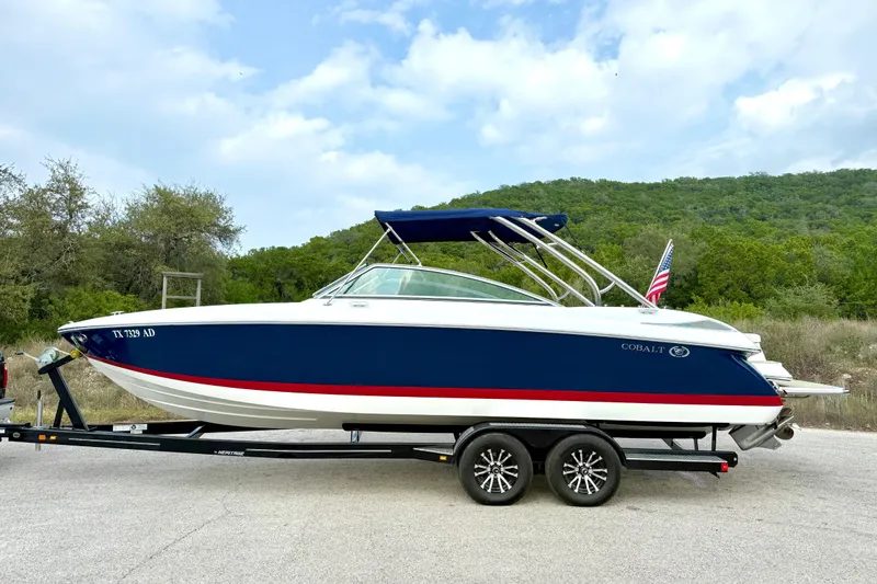 Slide: The Image of 2006 Cobalt 272 boat on trailer, blue and white design, parked outdoors. - 12