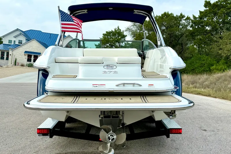 Slide: The Image of 2006 Cobalt 272 boat with American flag, parked on a driveway. - 14