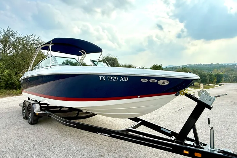 Slide: The Image of 2006 Cobalt 272 boat on trailer, blue and white with red stripe, parked outdoors. - 18
