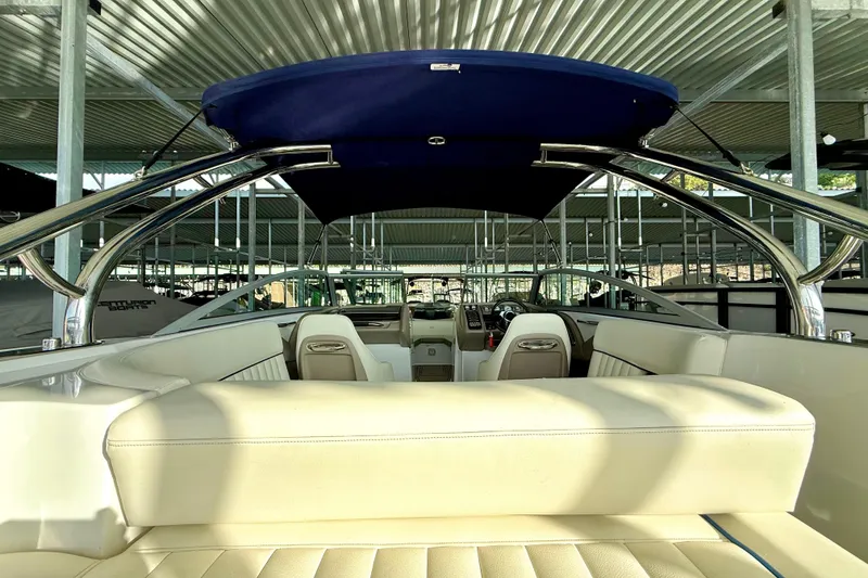 Slide: The Image of 2006 Cobalt 272 boat interior with beige seating and blue canopy in a marina. - 27