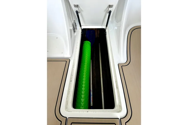 Slide: The Image of Storage compartment in a 2006 Cobalt 272 boat with green hose and hydraulic hinges. - 38
