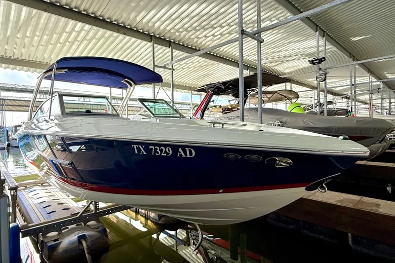 Slide: The Image of 2006 Cobalt 272 boat with blue canopy docked in a covered marina. - 53