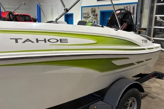 Slide: The Image of 2024 Tahoe T18 boat with green accents on a trailer in a showroom. - 2