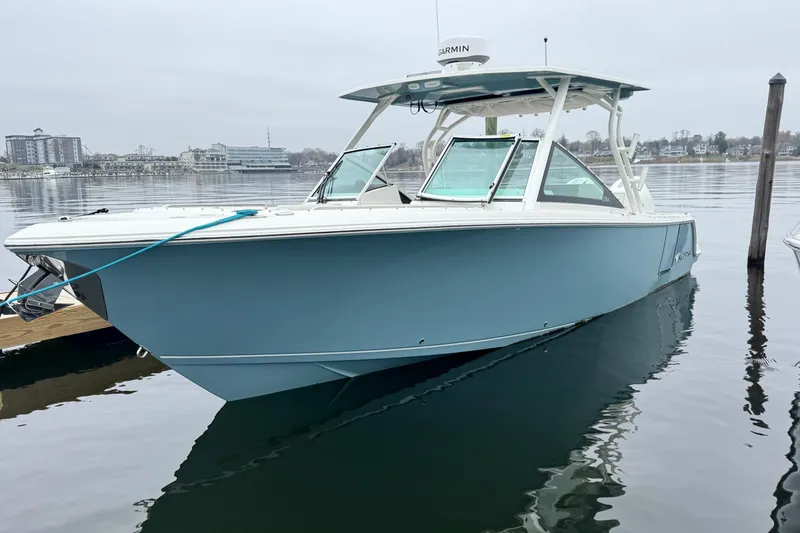 The Image of 2025 Sailfish 276 DC boat at sunset, reflecting on calm water near cityscape. - 0