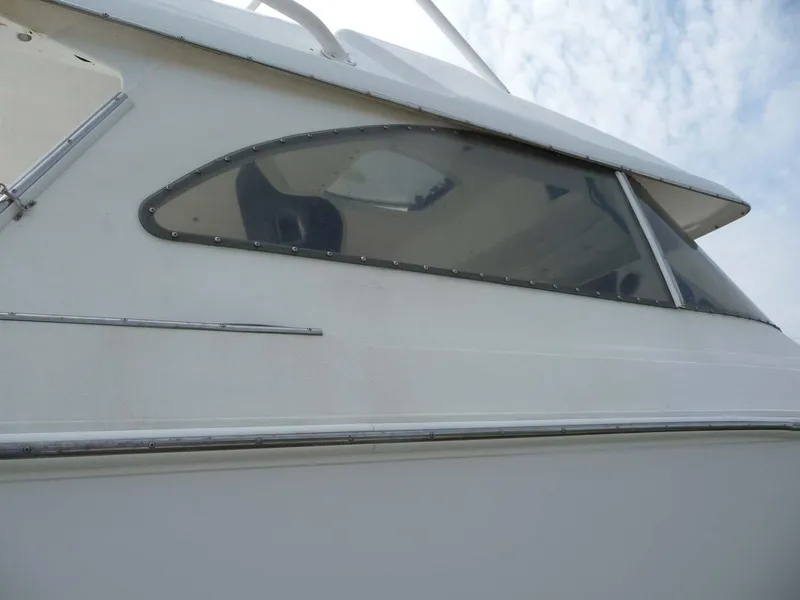 Slide: The Image of 1985 Wellcraft Scarab 34 boat, side view with window detail against cloudy sky. - 10