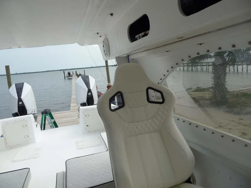 Slide: The Image of 1985 Wellcraft Scarab 34 boat interior with white seating, docked by a serene waterfront. - 17