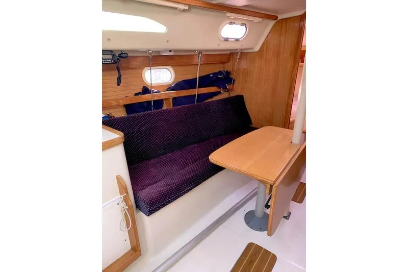 Slide: The Image of Interior of 2006 Catalina 28 sailboat with wooden table and cushioned seating. - 6