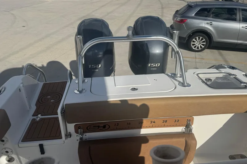 Slide: The Image of 2022 Sea Hunt Gamefish 25 boat with dual Yamaha 150 engines, docked near a silver car. - 8