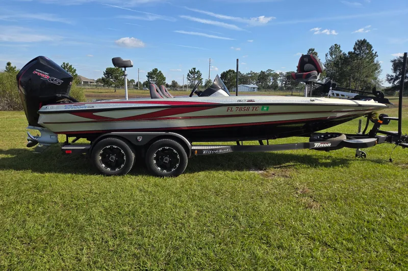 The Image of 2021 Triton 20 TrX bass boat on trailer, parked on grass under clear sky. - 0