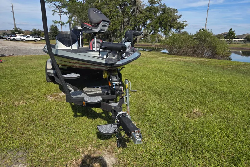 Slide: The Image of 2021 Triton 20 TrX boat on trailer, equipped with Minn Kota motor, parked on grass. - 4