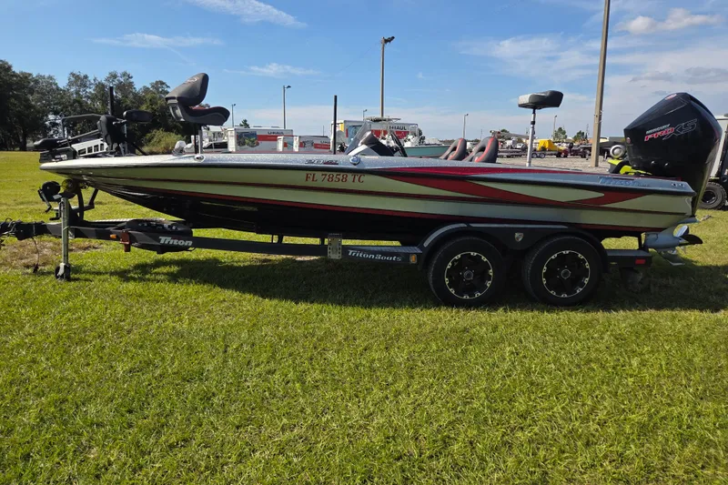 Slide: The Image of 2021 Triton 20 TrX boat interior with dual seats and steering wheel on grass. - 7