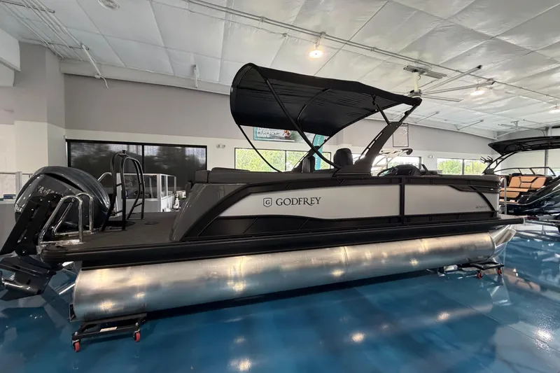 The Image of 2026 Godfrey Monaco 235ULC pontoon boat displayed indoors with sleek design and canopy. - 0