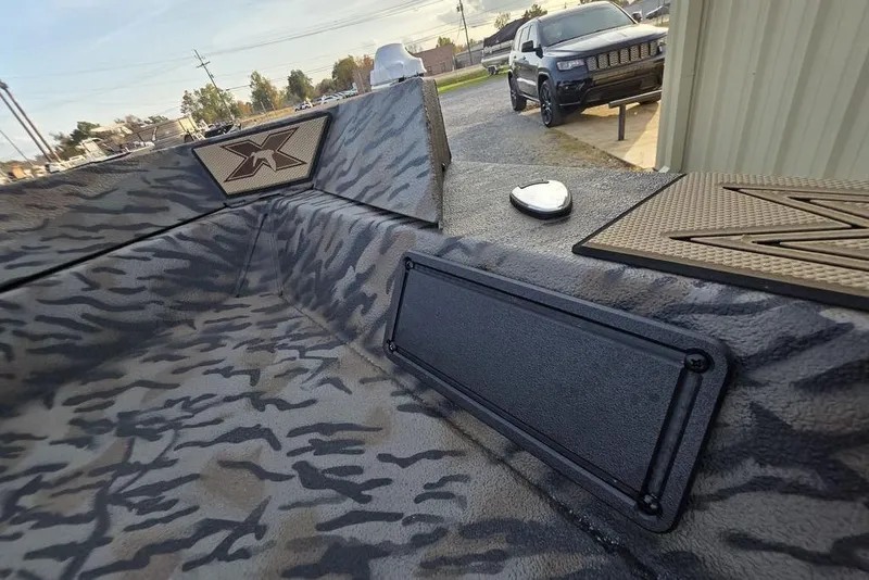 Slide: The Image of 2026 Xpress X18DB boat with camouflage pattern on gravel surface. - 28