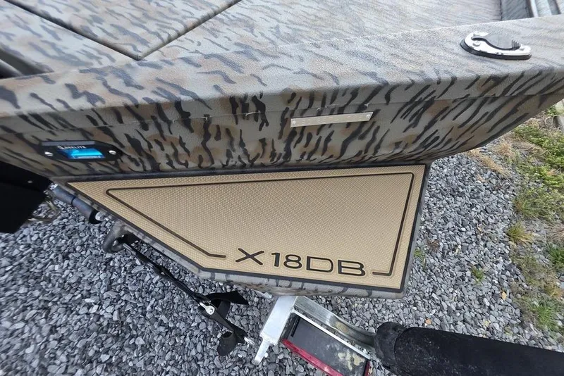 Slide: The Image of 2026 Xpress X18DB boat with Yamaha outboard motor, parked on gravel near a building. - 8