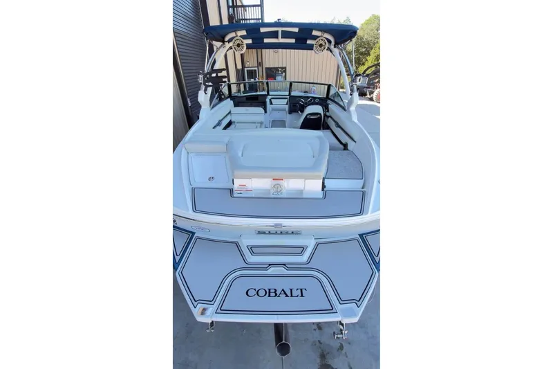 Slide: The Image of 2020 Cobalt CS23 Surf boat with blue accents, rear view in a marina setting. - 12