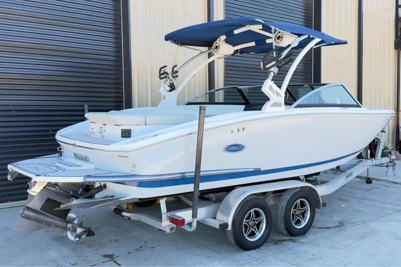 Slide: The Image of 2020 Cobalt CS23 Surf boat on trailer with blue canopy, parked near garage. - 4