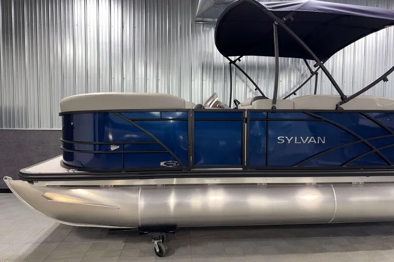 Slide: The Image of 2026 Sylvan Mirage 820 Cruise pontoon boat with blue exterior and canopy in a showroom. - 18