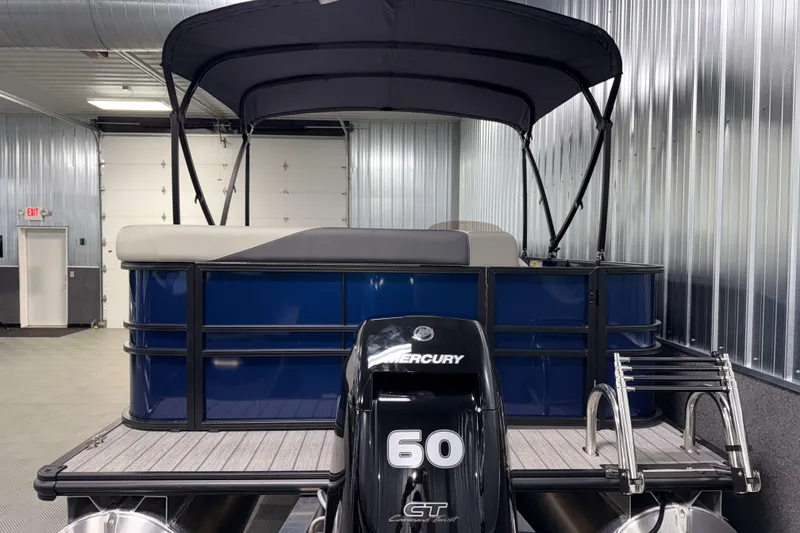 Slide: The Image of 2026 Sylvan Mirage 820 Cruise pontoon boat with Mercury 60 engine in a metal-walled garage. - 22