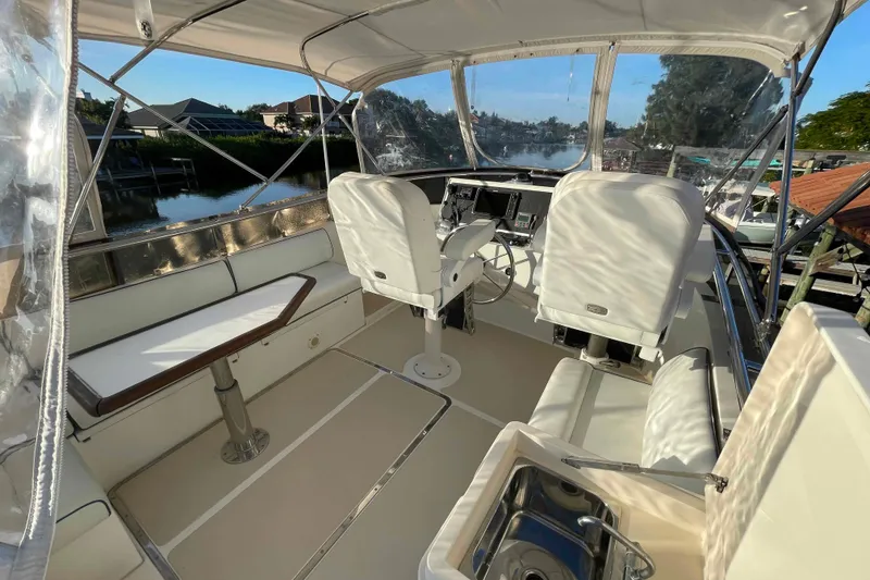 Slide: The Image of 2002 President Trawler cockpit with white seating, steering console, and waterfront view. - 14