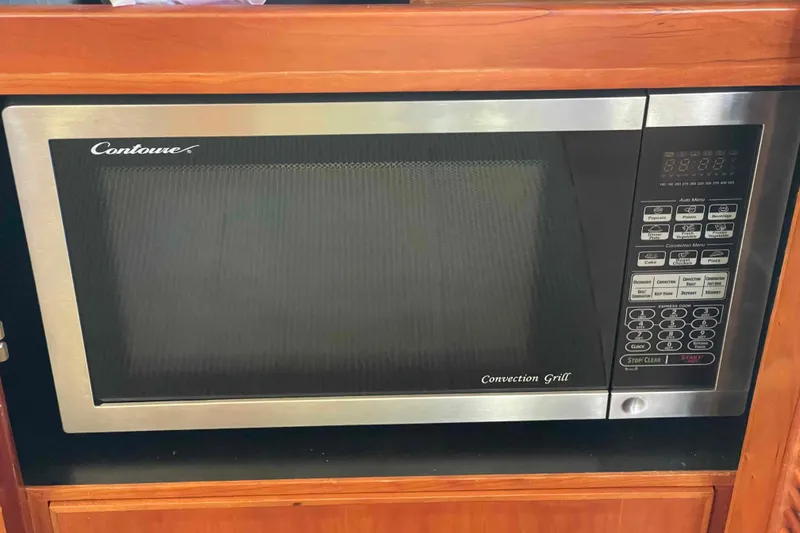 Slide: The Image of Contoure convection grill microwave in wooden cabinet, featuring digital controls and stainless steel finish. - 56