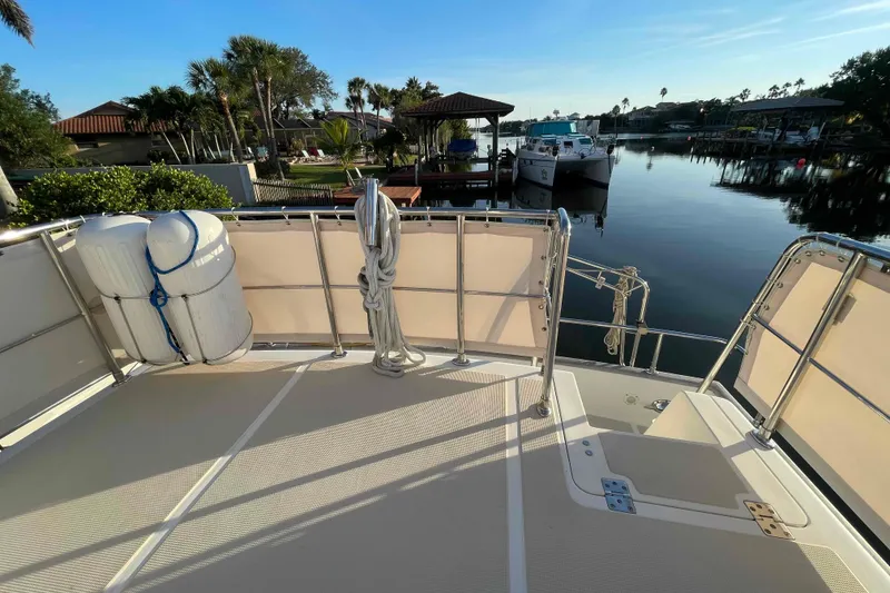 Slide: The Image of 2002 President Trawler deck overlooking serene marina with docked boats and lush greenery. - 79