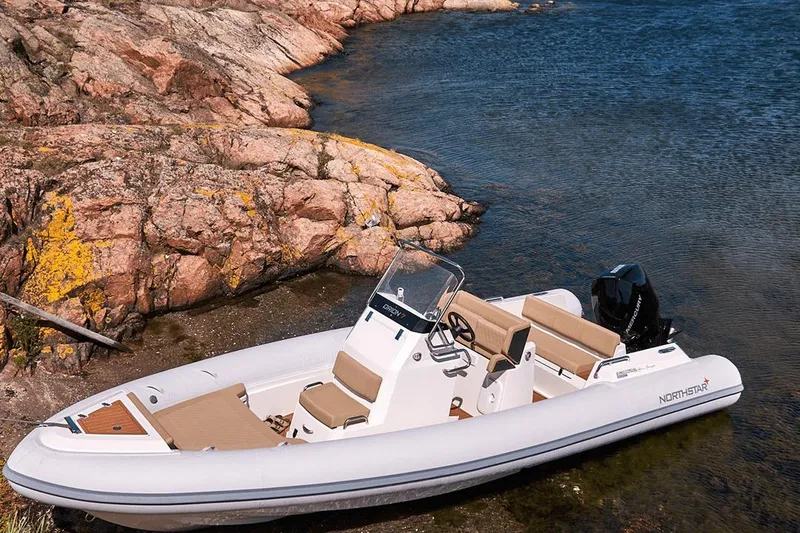 Slide: The Image of 2026 Northstar Orion 7 boat docked by rocky shoreline in clear water. - 7