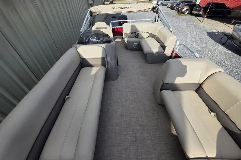 Slide: The Image of 2023 Sun Tracker Party Barge 18 DLX interior with beige seating and spacious layout. - 6
