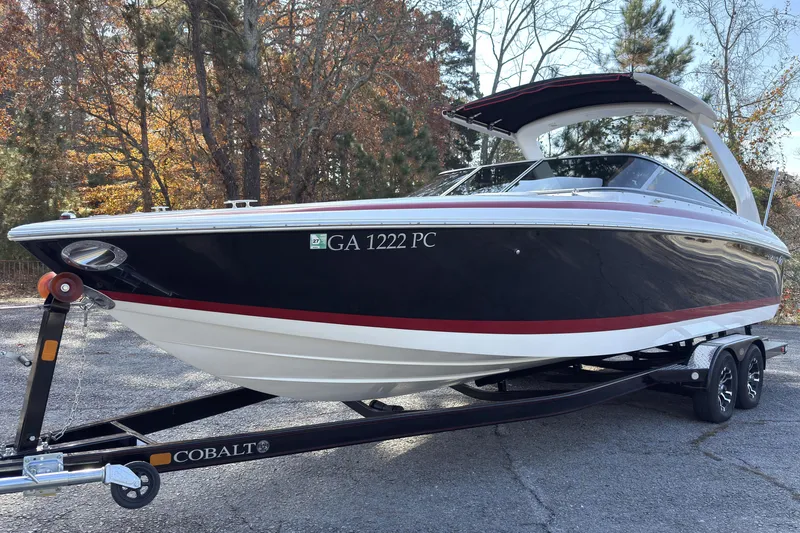 Slide: The Image of 2004 Cobalt 262 boat on trailer, parked outdoors with autumn trees in background. - 1