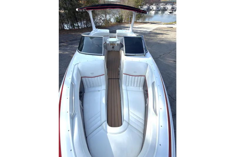Slide: The Image of 2004 Cobalt 262 boat with white seating and wooden deck, docked near a lake. - 15