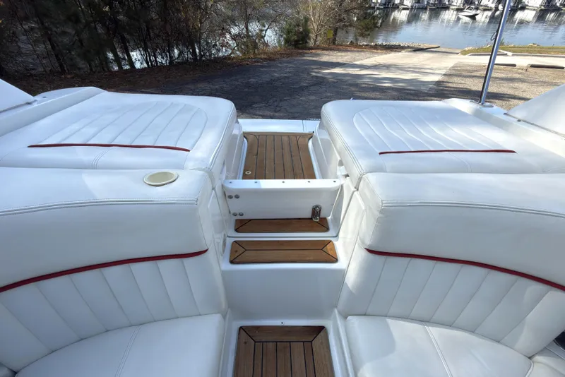 Slide: The Image of 2004 Cobalt 262 boat interior with white seating and wooden accents, near a marina. - 19