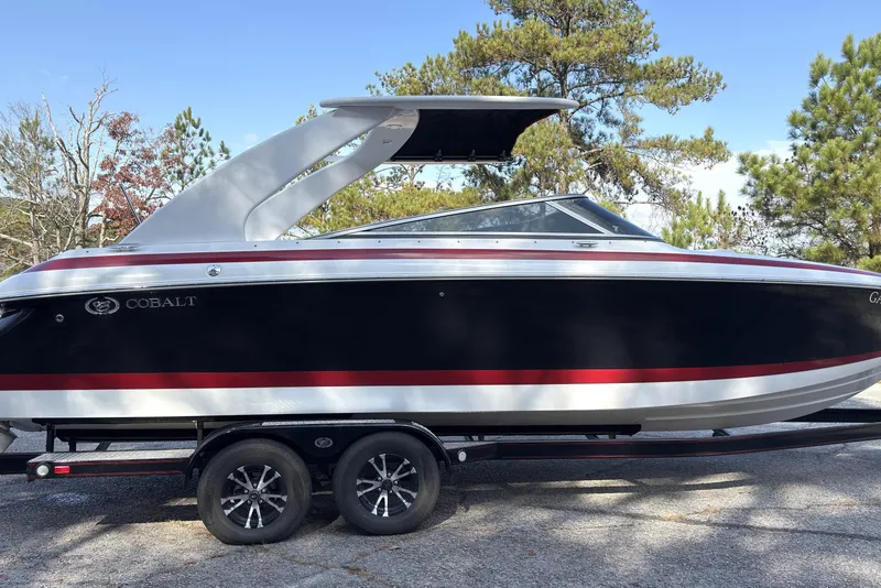 Slide: The Image of 2004 Cobalt 262 boat on trailer, black with red stripe, parked outdoors. - 2