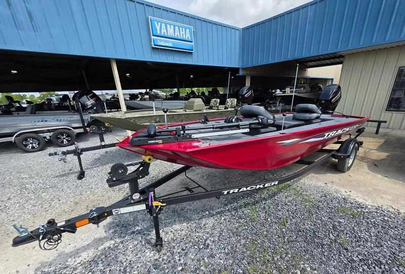 Slide: The Image of 2025 Tracker Panfish™ 17 boat in red, parked outside a Yamaha dealership. - 17