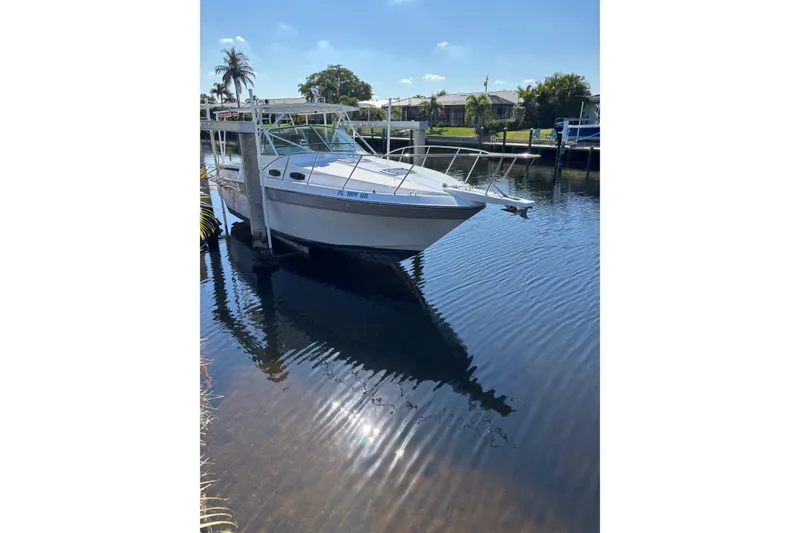 Slide: The Image of 1987 Chris Craft Amerosport boat docked on a sunny day, reflecting on calm water. - 2