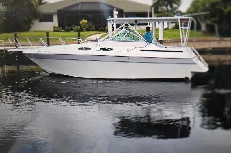 Slide: The Image of 1987 Chris Craft Amerosport boat docked on calm water, surrounded by lush greenery. - 20