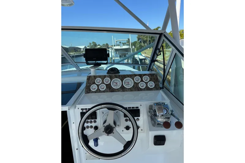Slide: The Image of 1987 Chris Craft Amerosport boat dashboard with steering wheel and gauges, docked at marina. - 8