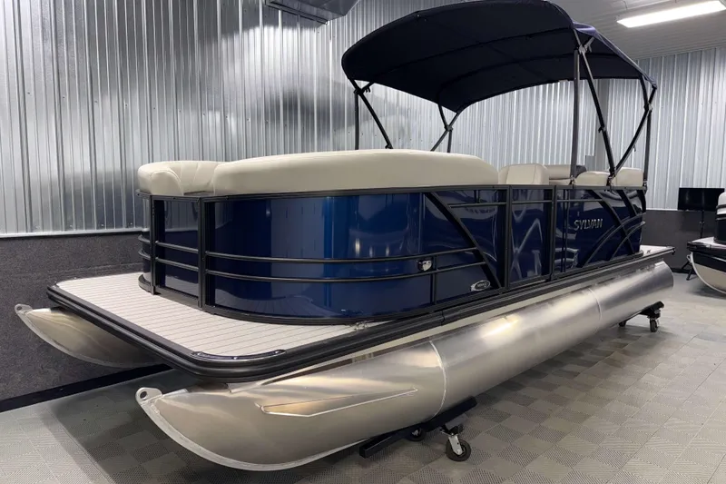 Slide: The Image of 2026 Sylvan Mirage 820 LZ pontoon boat with blue exterior and canopy in showroom. - 16