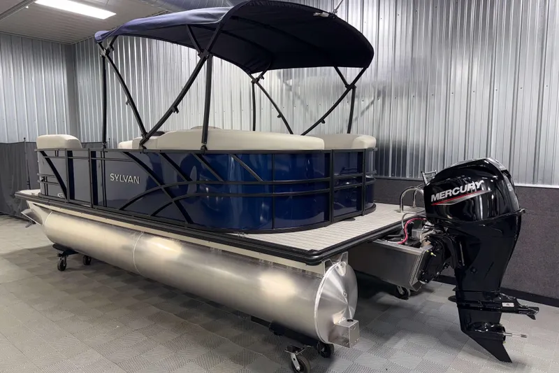Slide: The Image of 2026 Sylvan Mirage 820 LZ pontoon boat with Mercury outboard motor in a garage. - 21